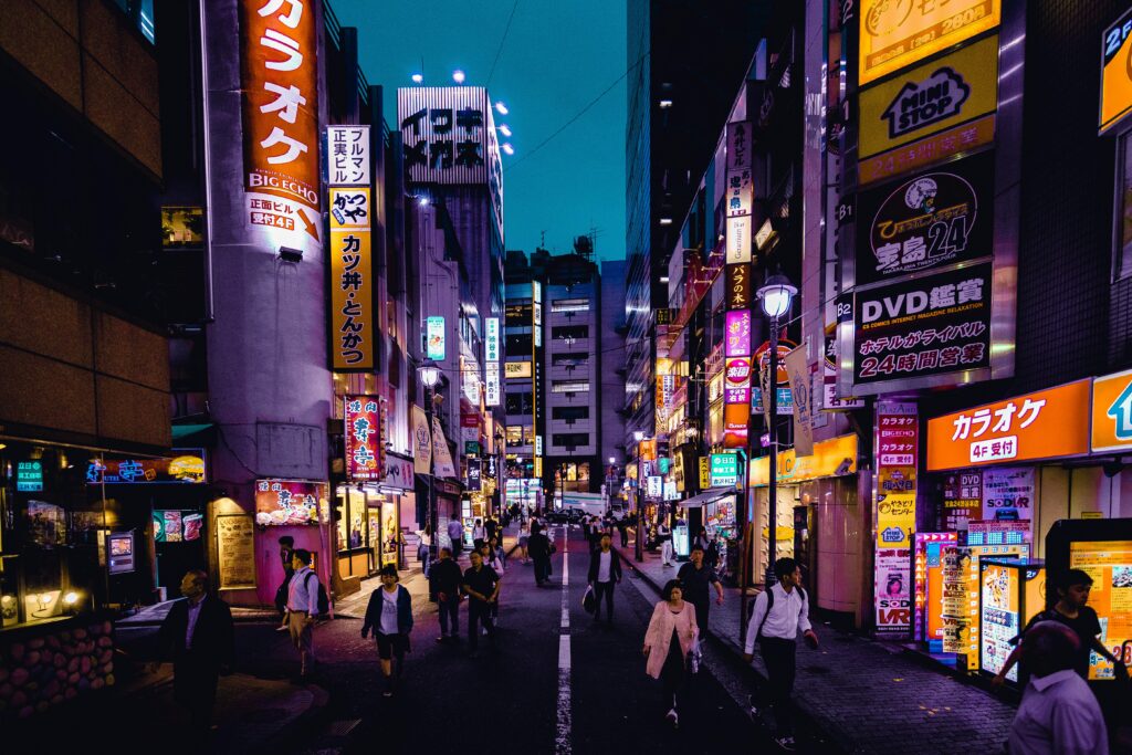 Explore the lively streets of Shinjuku, Tokyo at night with colorful lights and bustling activity.